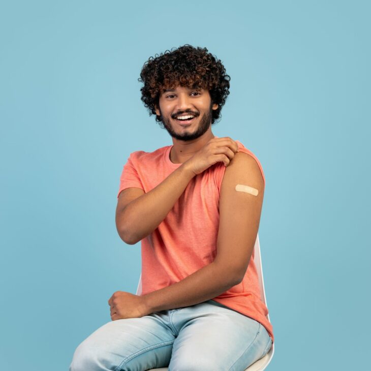 Young Indian man with orange shirt and Band-Aid on left bicept