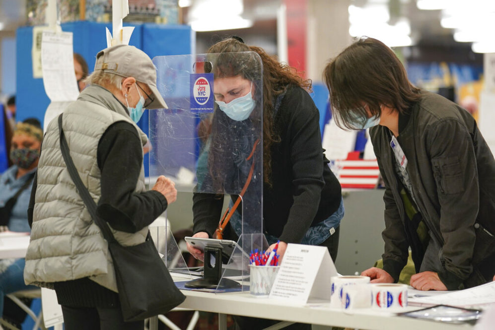 Poll workers help voters at a polling place in New York, Tuesday, Nov. 2, 2021. On Tuesday, voters in New York backed a right to clean air and water, as one of among roughly two dozen statewide ballot measures considered by voters across the U.S. (AP Photo/Seth Wenig)