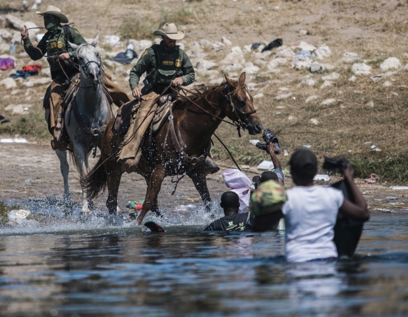 In this Sept. 19, 2021, file photo, U.S. Customs and Border Protection mounted officers attempt to contain migrants as they cross the Rio Grande from Ciudad Acuña, Mexico, into Del Rio, Texas. The Border Patrol's treatment of Haitian migrants, they say, is just the latest in a long history of discriminatory U.S. policies and of indignities faced by Black people, sparking new anger among Haitian Americans, Black immigrant advocates and civil rights leaders.( AP Photo/Felix Marquez, File)