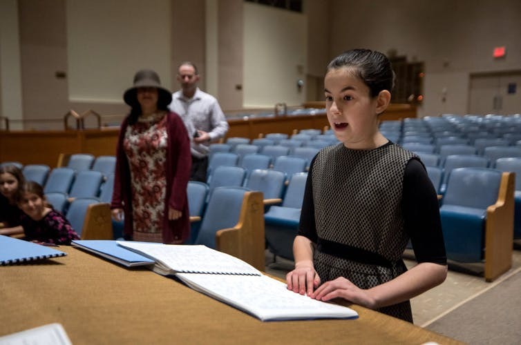 Batya Sperling Milner, who is blind, recites her Torah portion during rehearsal for her bat mitzvah ceremony at Ohev Shalom, an Orthodox synagogue in Washington, D.C. A computer programmer added the Torah chant code to the braille Torah so she could learn to recite. Evelyn Hockstein/For The Washington Post via Getty Image