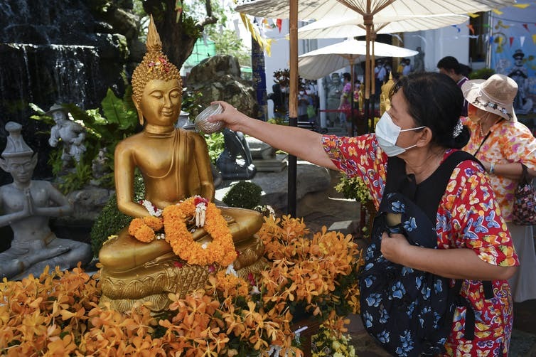 A woman pours scented water on a Buddha statue during Songkran at the Wat Pho temple in Bangkok, Thailand. Anusak Laowilas/NurPhoto via Getty Image