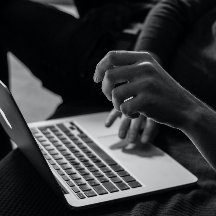 black and white photo of person's hands on laptop