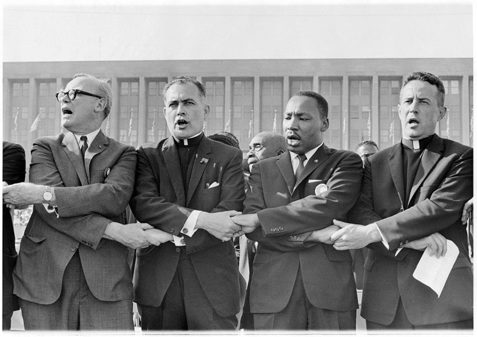 The Rev. Theodore Hesburgh, center left, holds hands with the Rev. Martin Luther King Jr. while singing “We Shall Overcome” during a civil rights rally at Soldier Field in Chicago on June 21, 1964. Photo courtesy of OCP Media