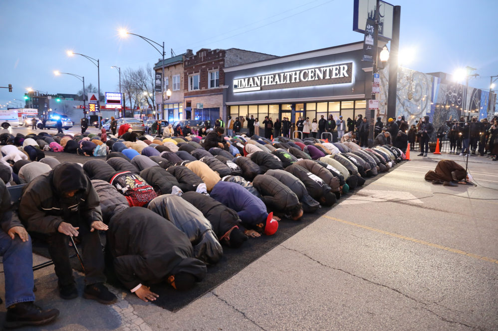Group bowing on knees in prayer on closed Chicago street for event
