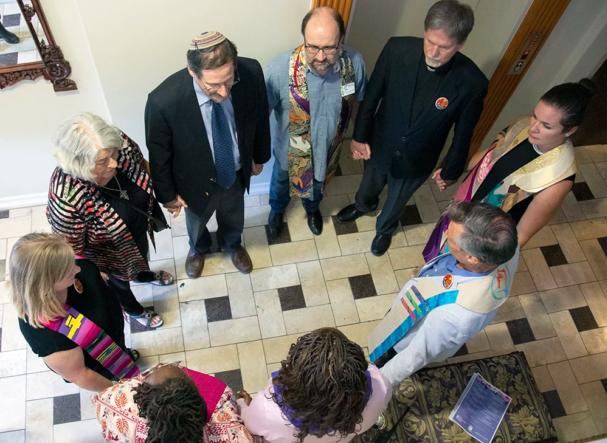 Interfaith leaders stand in circle, holding hands