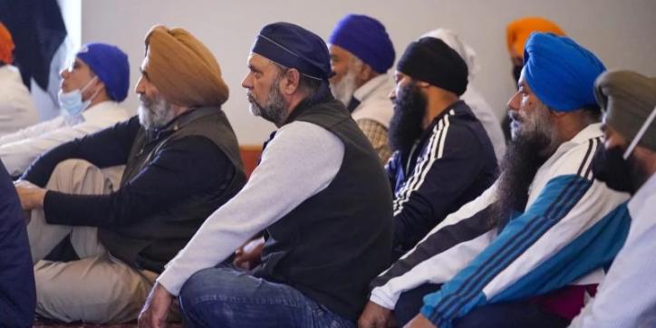 Sikh men in turbans sitting on floor in crowd
