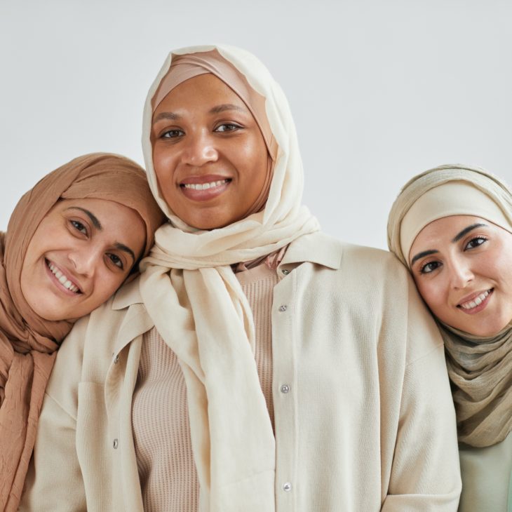 Three women in hijabs smiling at camera