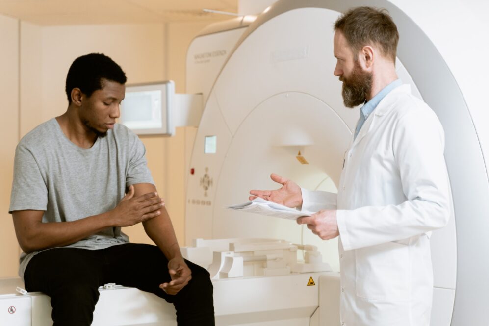 Doctor speaking with patient next to MRI machine.