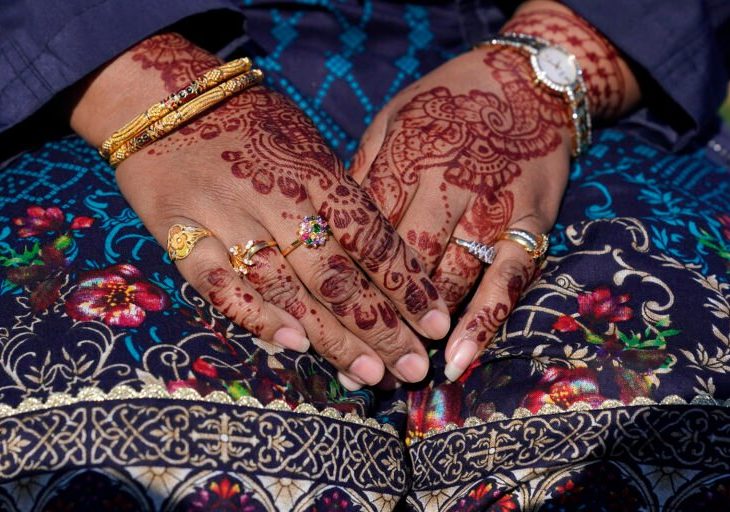 Hands on lap with jewelry and henna on them