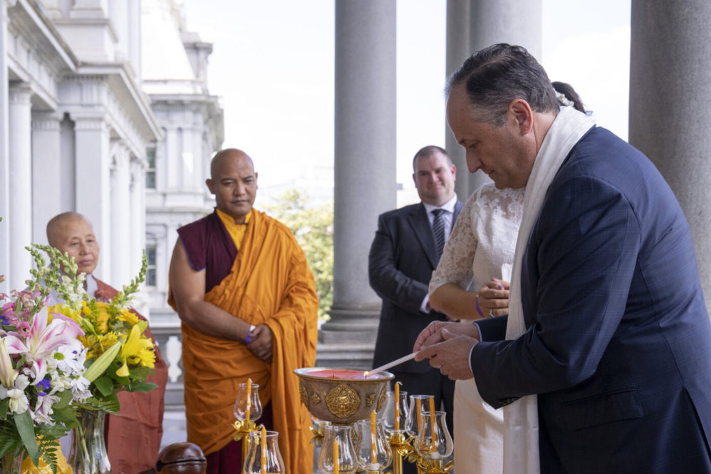Emhoff lights candle with Buddhist monks standing in the background