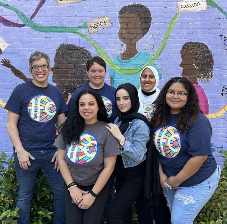 Group of students standing in front of mural on side of building