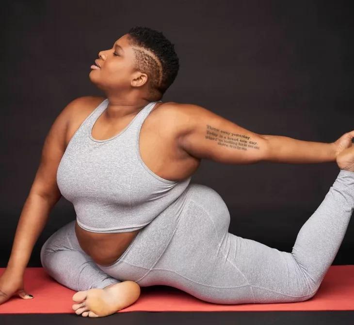 Jessamyn doing a yoga pose on a mat in a matching grey outfit