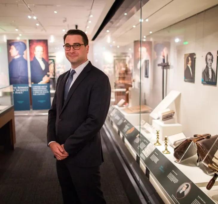 Peter standing in hall of museum with items in glass cases