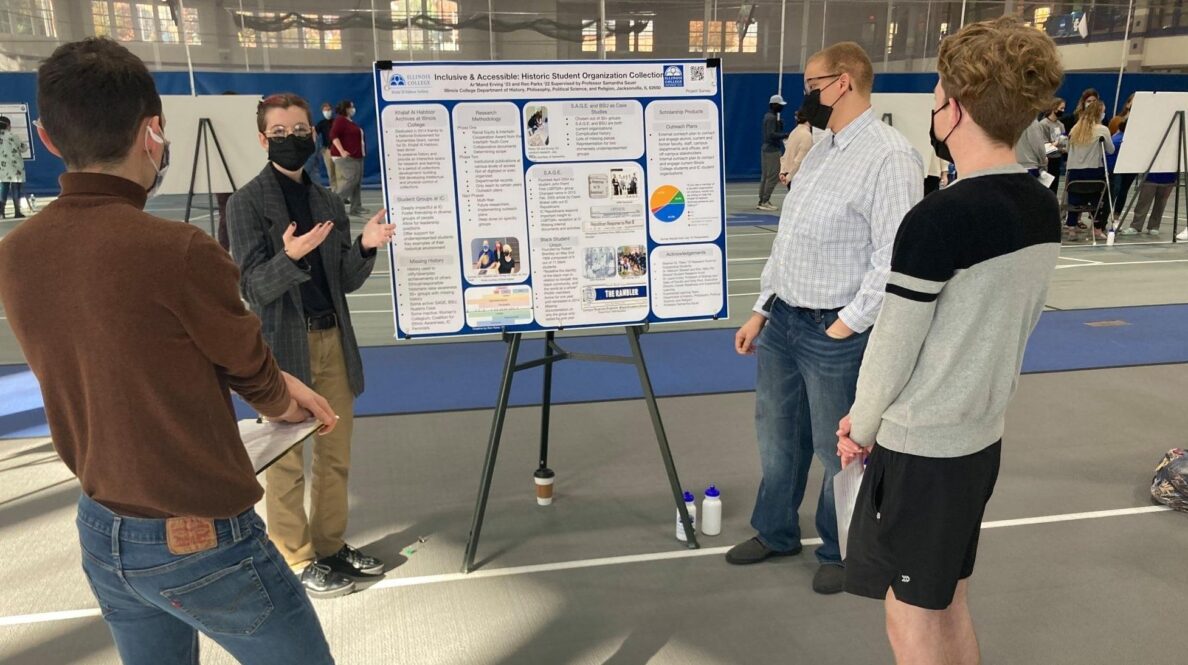 Two people looking at poster board presentation, two people presenting