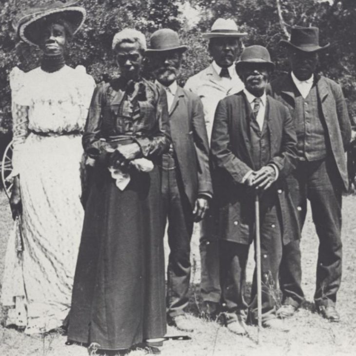 Group of people standing together in dresses and suits in black and whitephoto