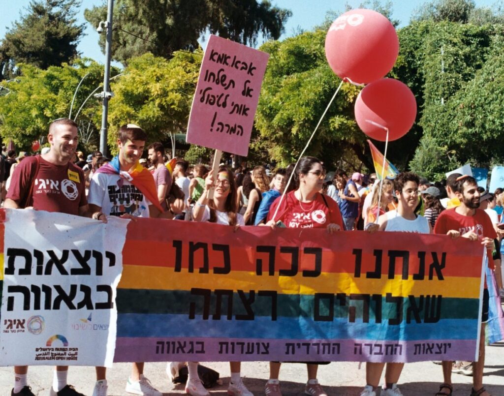 At the 2022 Jerusalem March for Pride and Tolerance., marchers hold a large rainbow sign that reads, “We are just like the Creator wanted us to be.” Another sign (left) says that “If G-d created us, why would G-d reject us?”