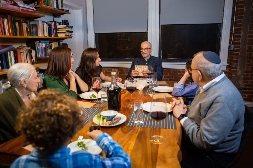 A Jewish American family celebrates Passover together.  The Seder leader holds up the middle matzo before breaking it. (halbergman/Getty)