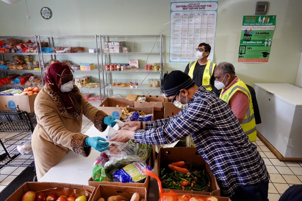 GLENDALE HEIGHTS, ILLINOIS - APRIL 11: Workers help to distribute food to those in need at the ICNA Relief Food Pantry after on April 11, 2020 in Glendale Heights, Illinois. The relief organization's demand for food has spiked tenfold in 2020 due to the pandemic. One of the volunteers stated that people who used to donate to the pantry are now coming in for donations. (Photo by Scott Olson/Getty Images)