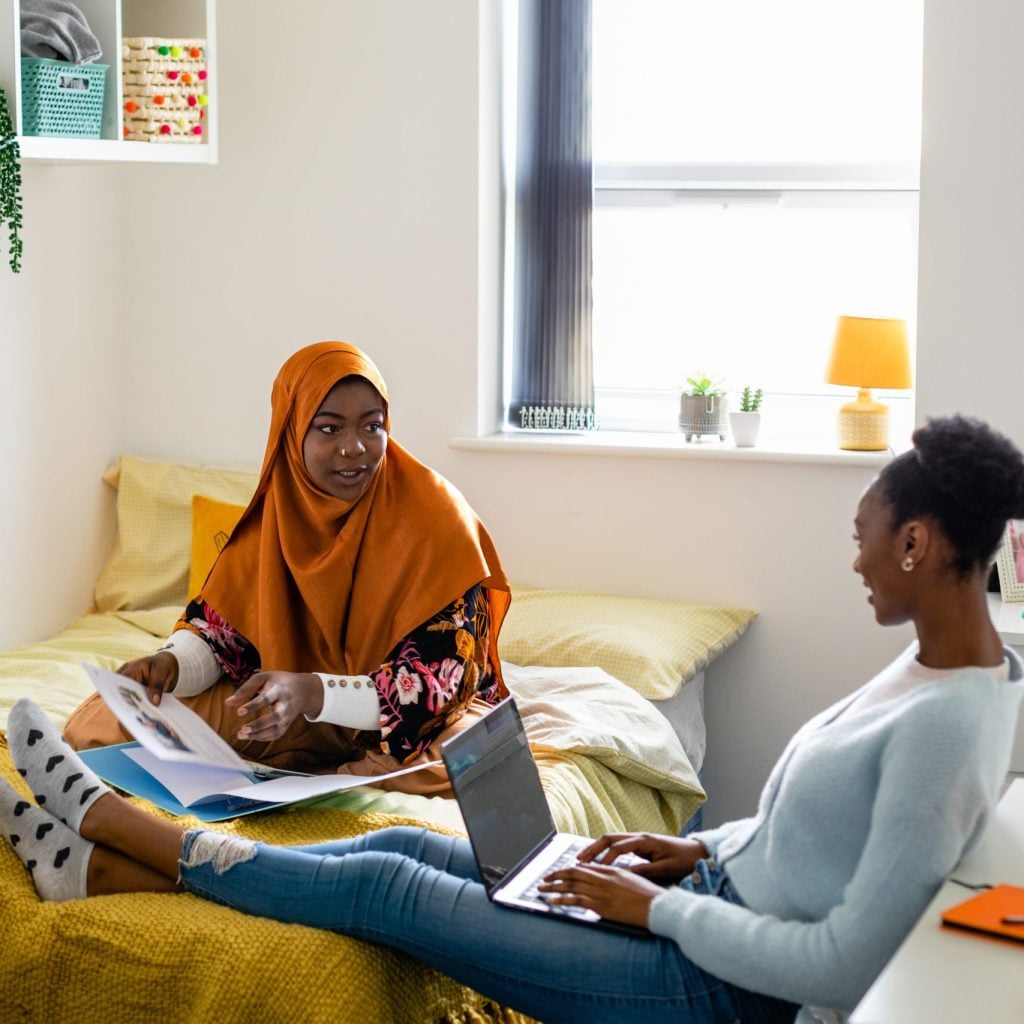 Two student friends sitting in dorm, studying together.