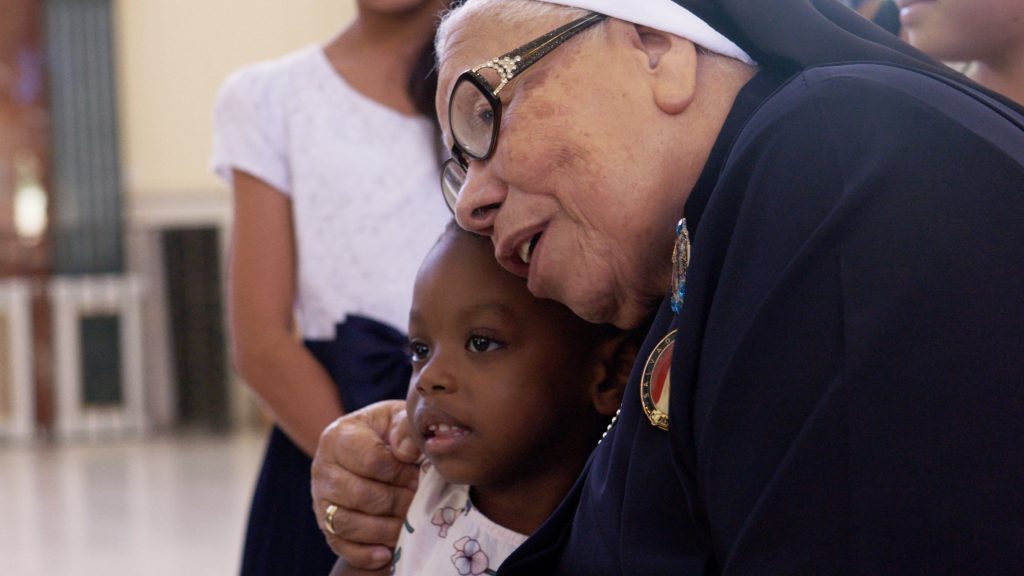 Still of Sister María Rosa Leggol of Honduras hugging a child in the documentary, “With This Light." Photo courtesy of press kit.
