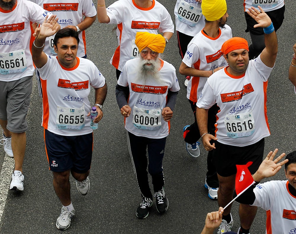 Centenarian marathon runner Fauja Singh, center, originally from Beas Pind, in Jalandhar, India but who now lives in London, runs in a 10-kilometer race, held as part of the annual Hong Kong Marathon, in Hong Kong, on Feb. 24, 2013. (AP Photo/Kin Cheung)