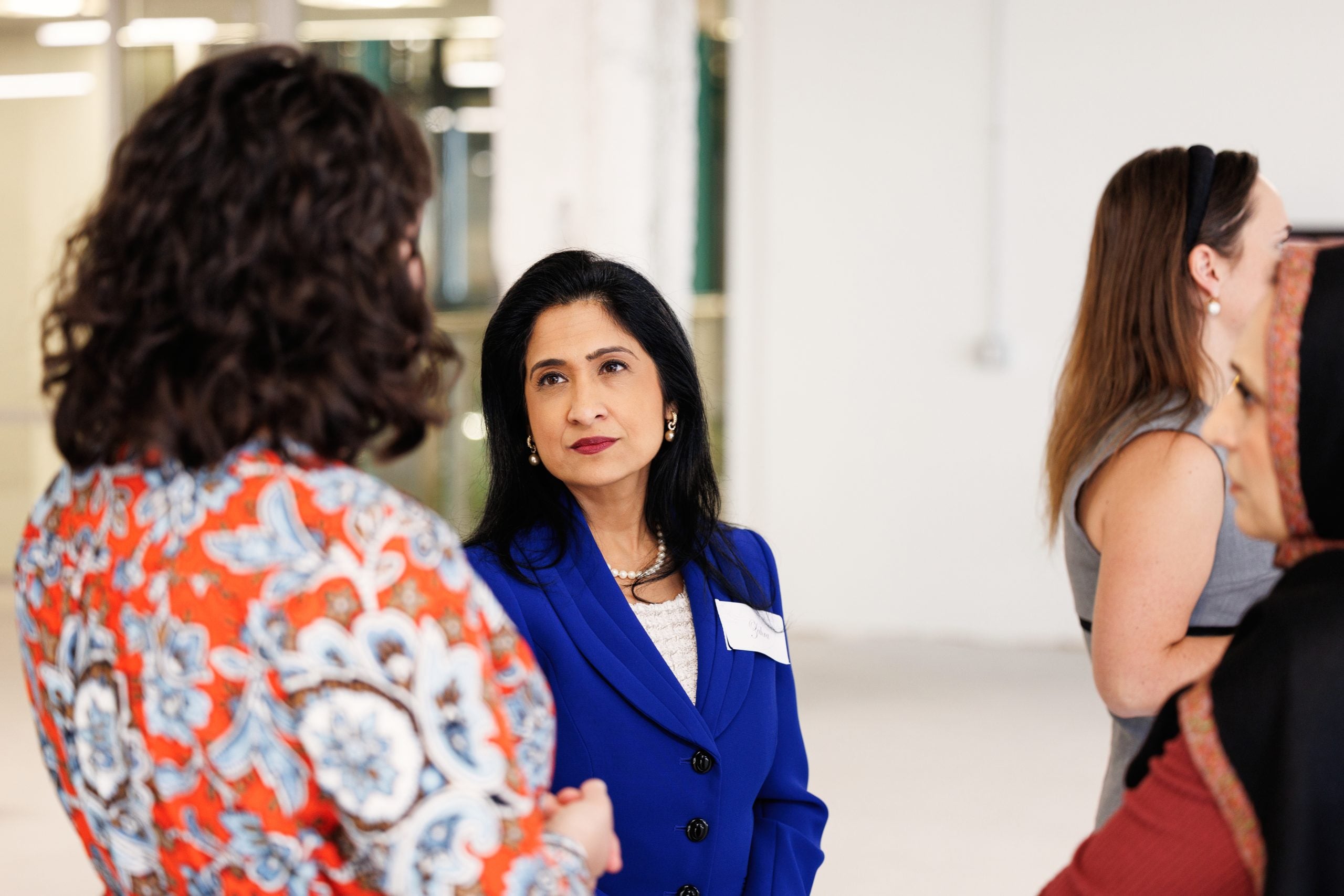 Zahra Jamal, Director of Workplace Strategy, speaks with Rebecca Russo, Vice President of Higher Education Strategy, at Interfaith America's 2025 Staff Thanksgiving Potluck. (Kelly Feldmiller, November 2025)
