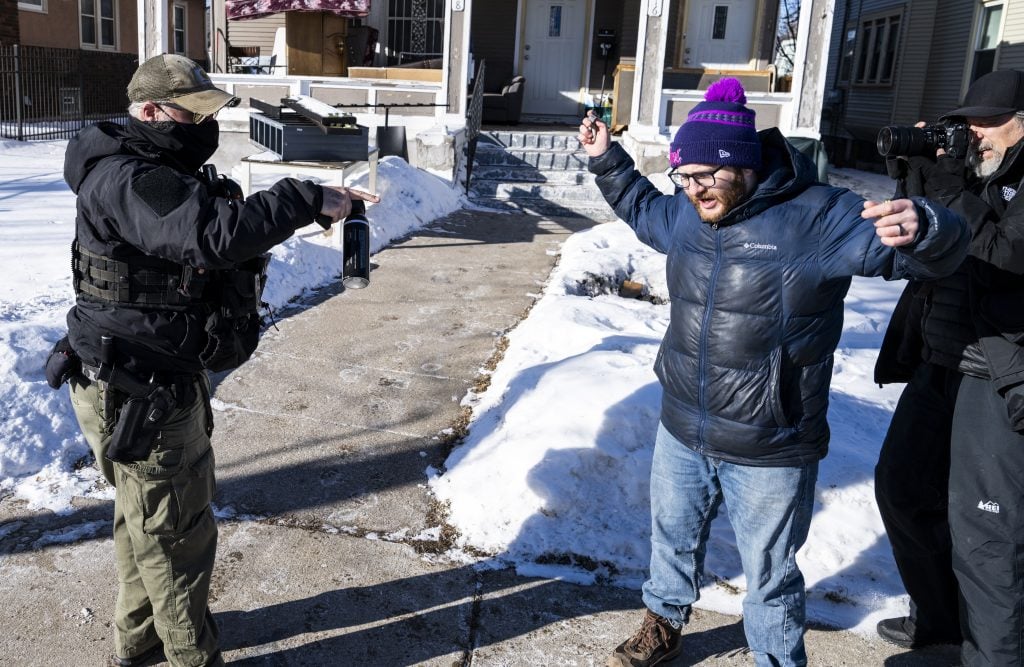 MINNEAPOLIS, MINNESOTA - JANUARY 28: An observer confronts an ICE agent as they knock on the door of a residence on January 28, 2026 in Minneapolis, Minnesota. DHS continues its immigration enforcement operations after the killings of Alex Pretti and Renee Nicole Good by federal law enforcement. (Photo by Stephen Maturen/Getty Images)