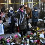 MINNEAPOLIS, MINNESOTA - JANUARY 14: June Pierce (C) prays during a vigil at a memorial near the site where Renee Good was killed a week ago on January 14, 2026 in Minneapolis, Minnesota. Good was fatally shot by an immigration enforcement agent during an incident in south Minneapolis on January 7. (Photo by Stephen Maturen/Getty Images)