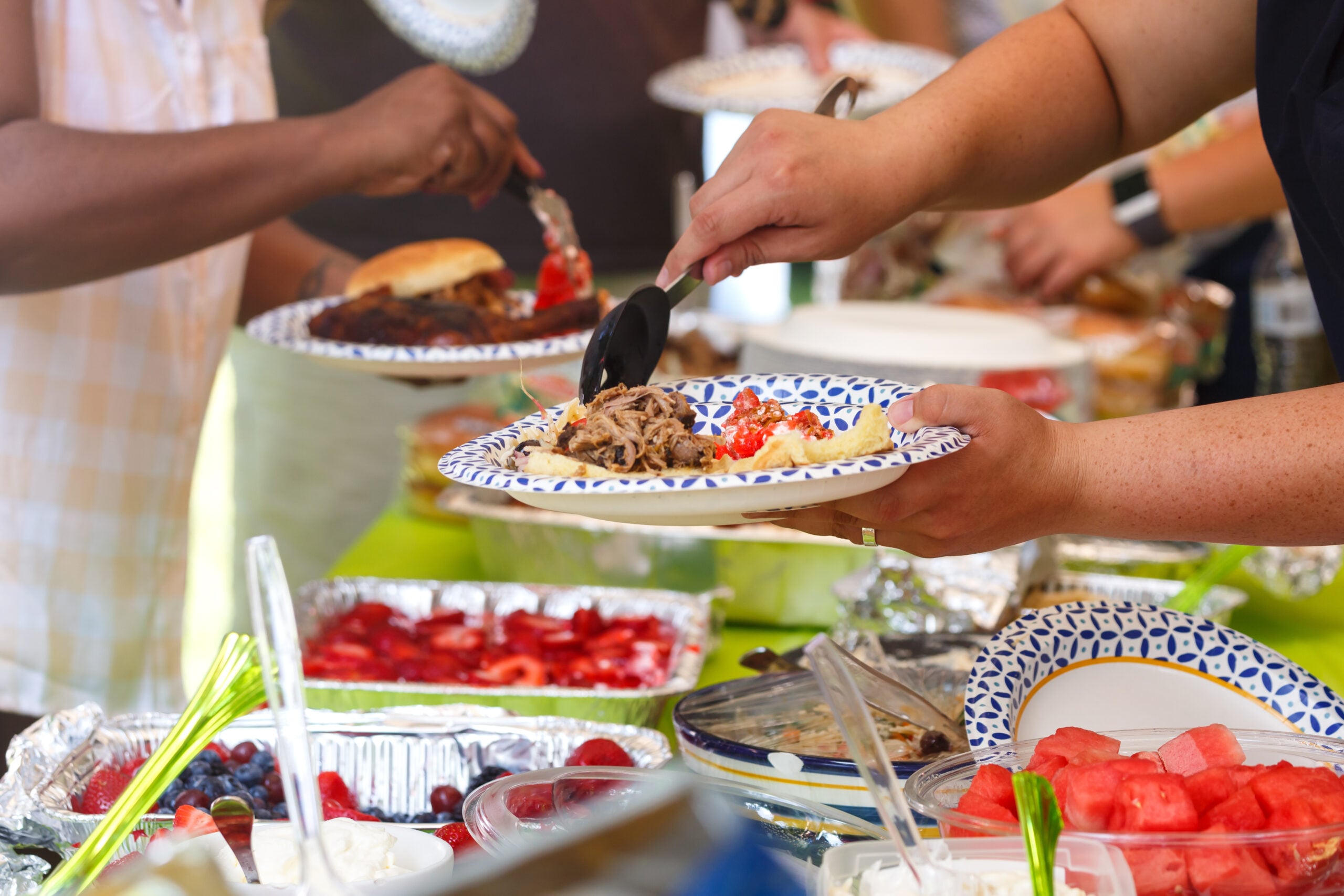 People sharing food at a summer potluck event (Linda Hughes Photography/Shutterstock)