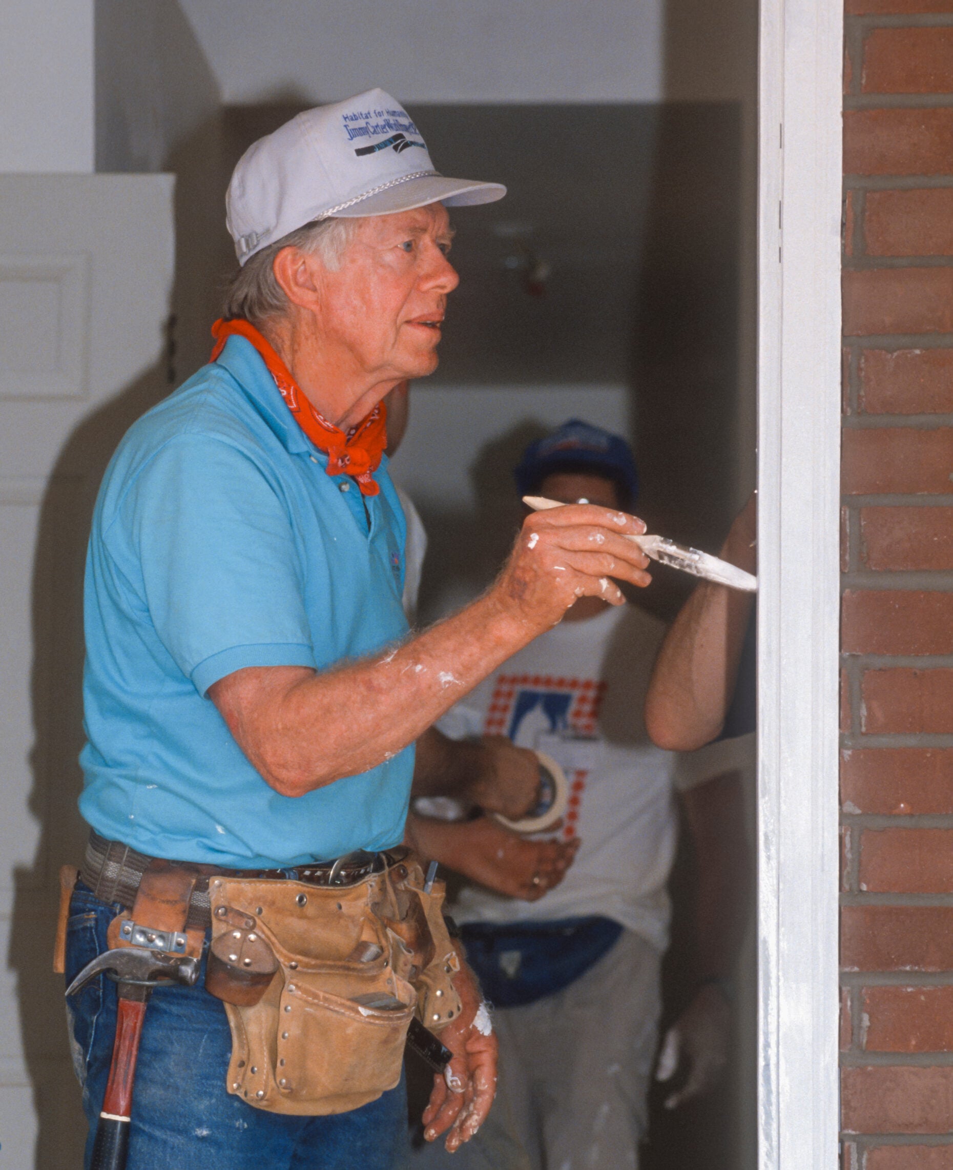 WASHINGTON, DC, USA - JUNE 18, 1992: President Jimmy Carter, Habitat for Humanity, painting door frame during project on Benning Road. (Rob Crandall/Shutterstock)