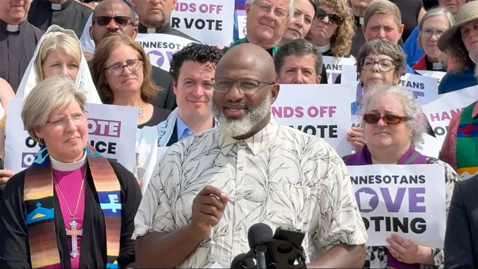 Clergy surrounds Imam Makram El-Amin, of Masjid An-Nur in Minneapolis, during a news conference, Tuesday, July 7, 2026,  at the Minneapolis State Capitol in Saint Paul, Minn. (Video screen grab)