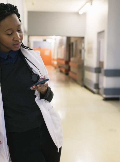Medical student checking their mobile phone in the hospital corridor during a quick break. (PixelCatchers/Getty)