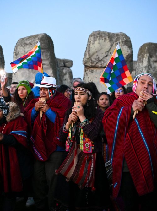 WILTSHIRE, ENGLAND - JUNE 21: People play pan pipes with Wiphala flags in the background at Stonehenge on June 21, 2023 in Wiltshire, England. In the Northern Hemisphere, the longest day of the year falls on the 21st of June. This day is often referred to as the Summer Solstice or Midsummer's Day. (Photo by Finnbarr Webster/Getty Images)