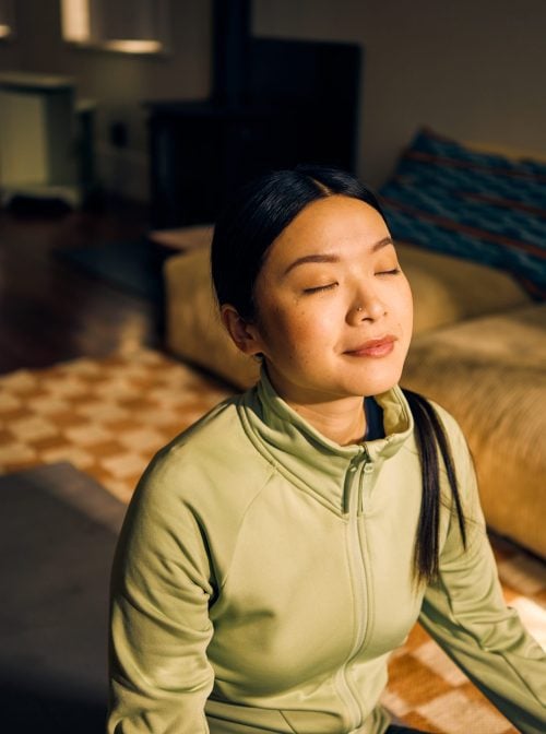 Person meditating in living room. (pixdeluxe/Getty Images)