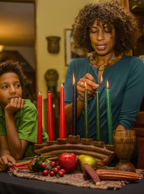 Family lighting kinara candles, celebrating Kwanzaa. (Sue Barr/Getty Images)