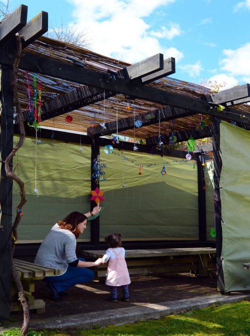 Jewish woman and child visiting their family sukkah in the Jewish festival of Sukkot. A Sukkah is a temporary structure where meals are taken for the week. (chameleonseye/	iStock / Getty Images Plus)