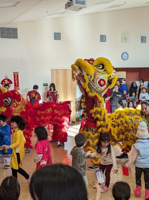 Children collect confetti from Lunar New Year dancers.